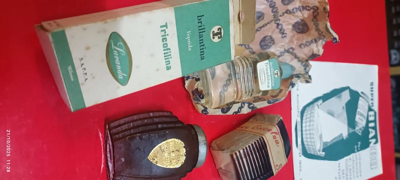 Collezionismo vintage. Set formato da una confezione di brillantina Tricofilina, una di brillantina Reginetta, un porta spazzolino, tre fogli pubblicitari di carta assorbente e una confezione di 12 pettinesse. 250g.