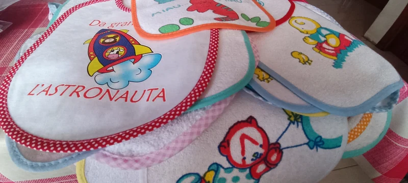 Cinque bavaglini assortiti, di puro cotone e cotone con gomma per pappa. 200g.